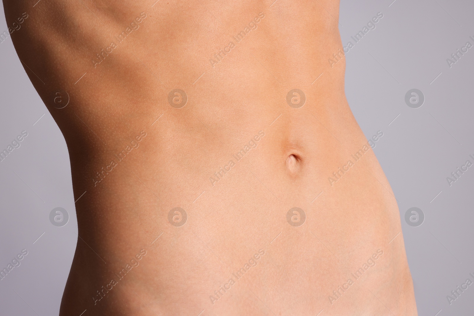 Woman with flat belly on grey background, closeup Photo of Woman with flat belly on grey background, closeup