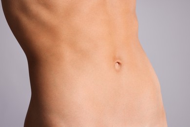 Photo of Woman with flat belly on grey background, closeup