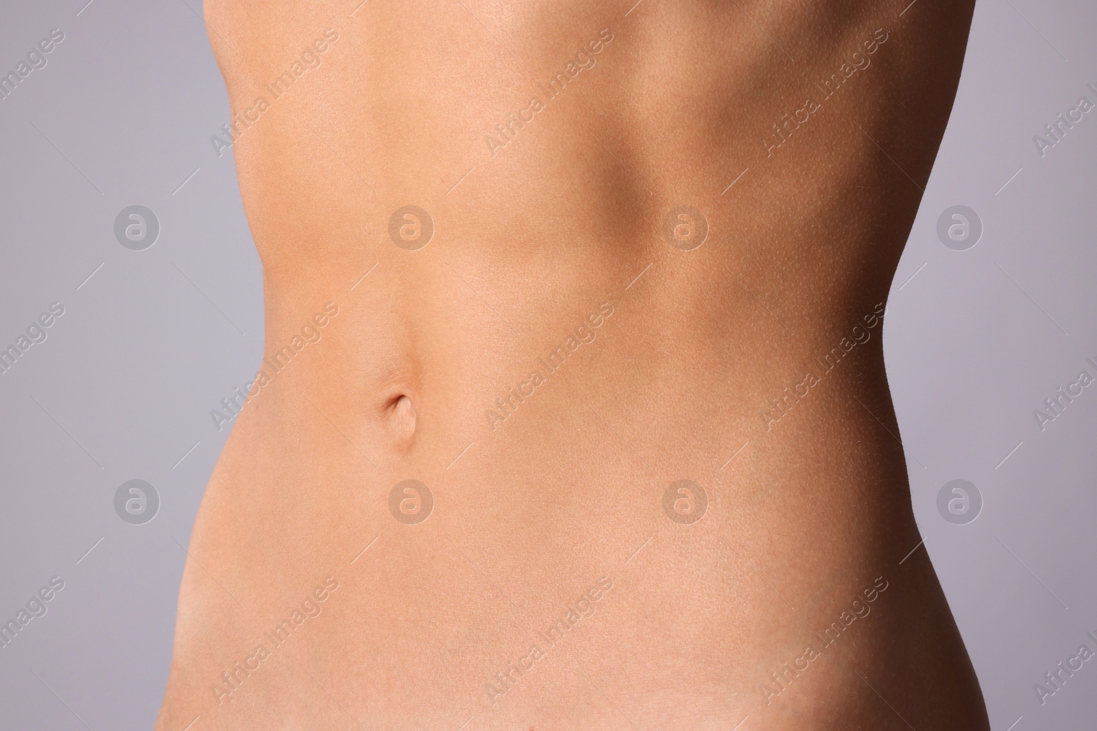 Woman with flat belly on grey background, closeup Photo of Woman with flat belly on grey background, closeup