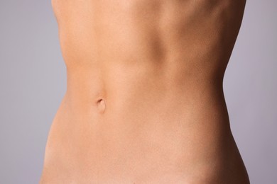 Photo of Woman with flat belly on grey background, closeup