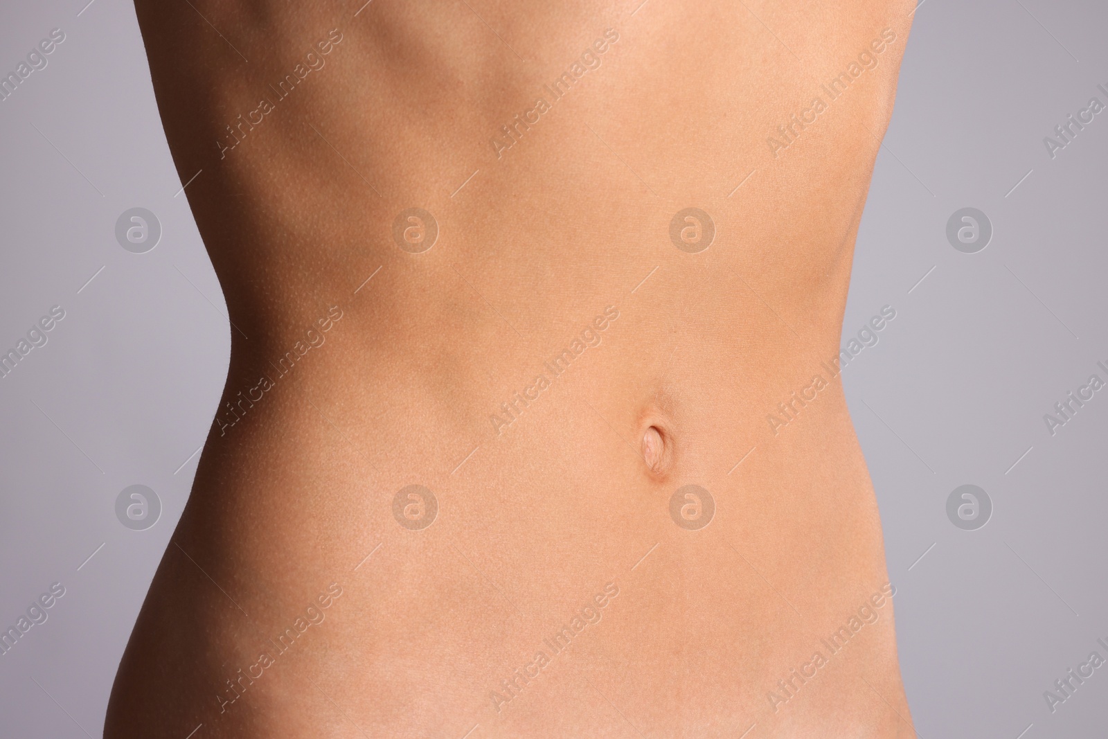 Woman with flat belly on grey background, closeup Photo of Woman with flat belly on grey background, closeup