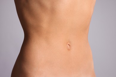 Photo of Woman with flat belly on grey background, closeup