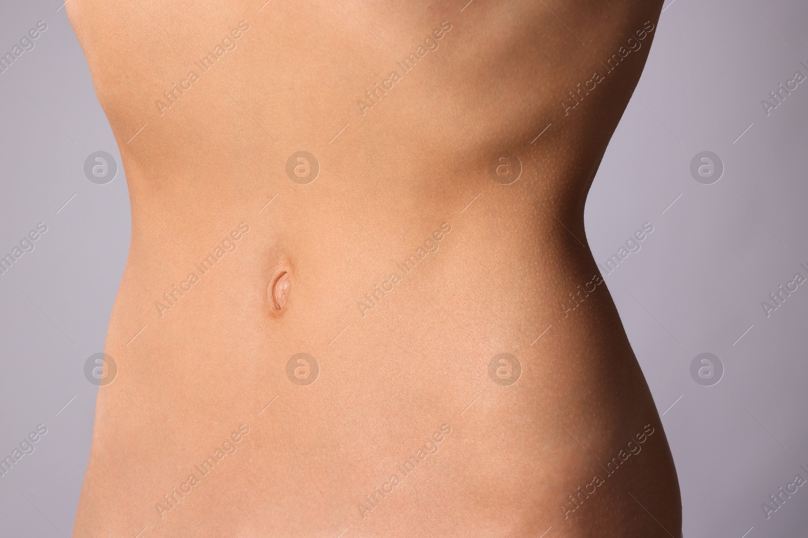 Woman with flat belly on grey background, closeup Photo of Woman with flat belly on grey background, closeup