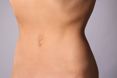 Photo of Woman with flat belly on grey background, closeup