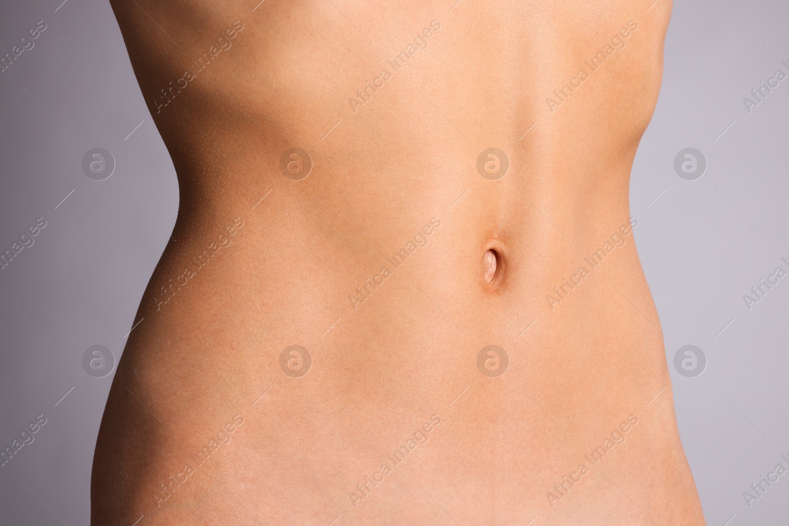 Woman with flat belly on grey background, closeup Photo of Woman with flat belly on grey background, closeup