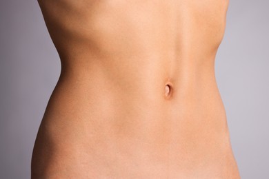 Photo of Woman with flat belly on grey background, closeup