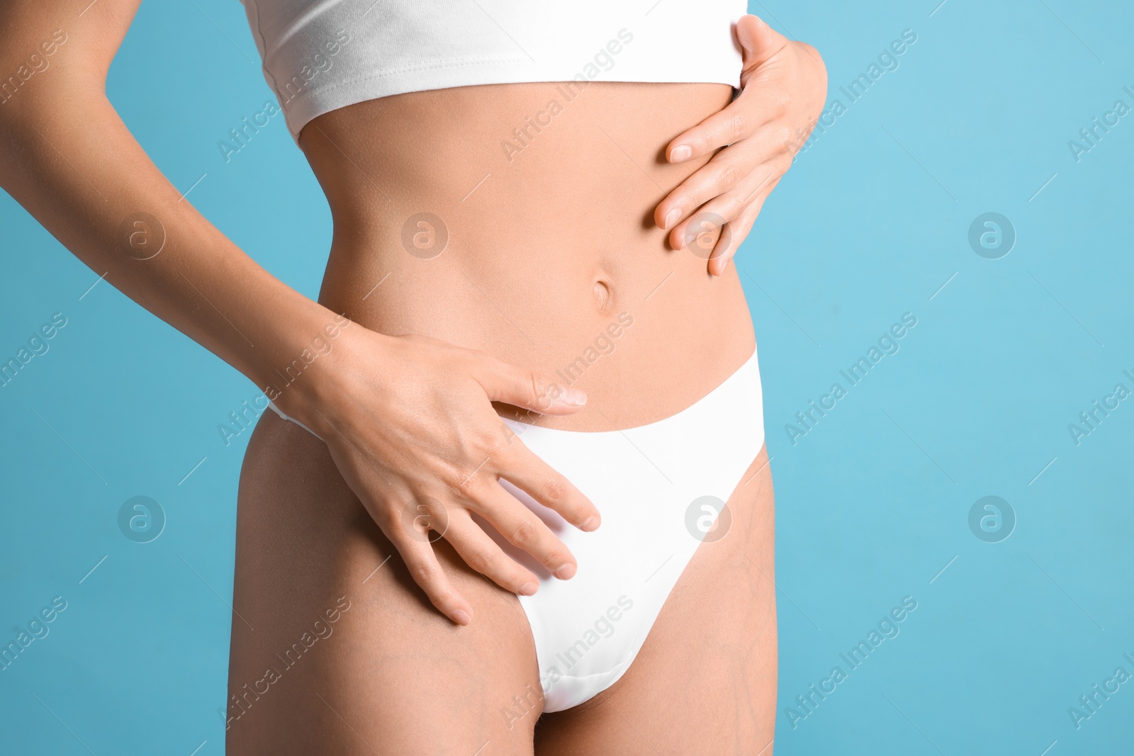 Woman with flat belly on light blue background, closeup Photo of Woman with flat belly on light blue background, closeup