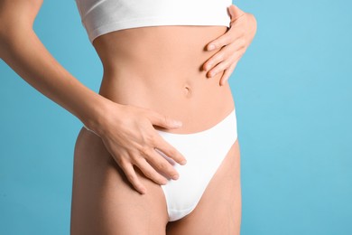 Photo of Woman with flat belly on light blue background, closeup