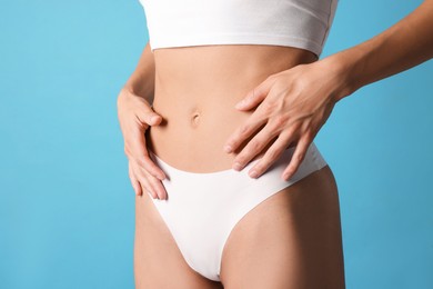 Photo of Woman with flat belly on light blue background, closeup