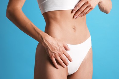 Photo of Woman with flat belly on light blue background, closeup