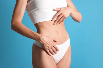 Photo of Woman with flat belly on light blue background, closeup