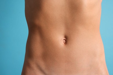 Photo of Woman with flat belly on light blue background, closeup