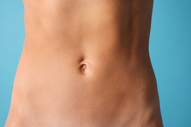 Photo of Woman with flat belly on light blue background, closeup