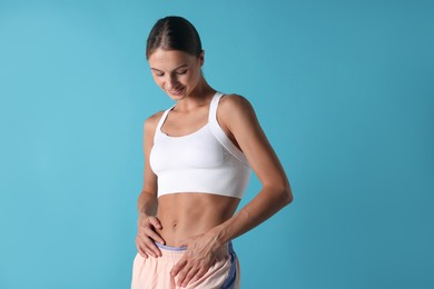 Photo of Woman with flat belly on light blue background