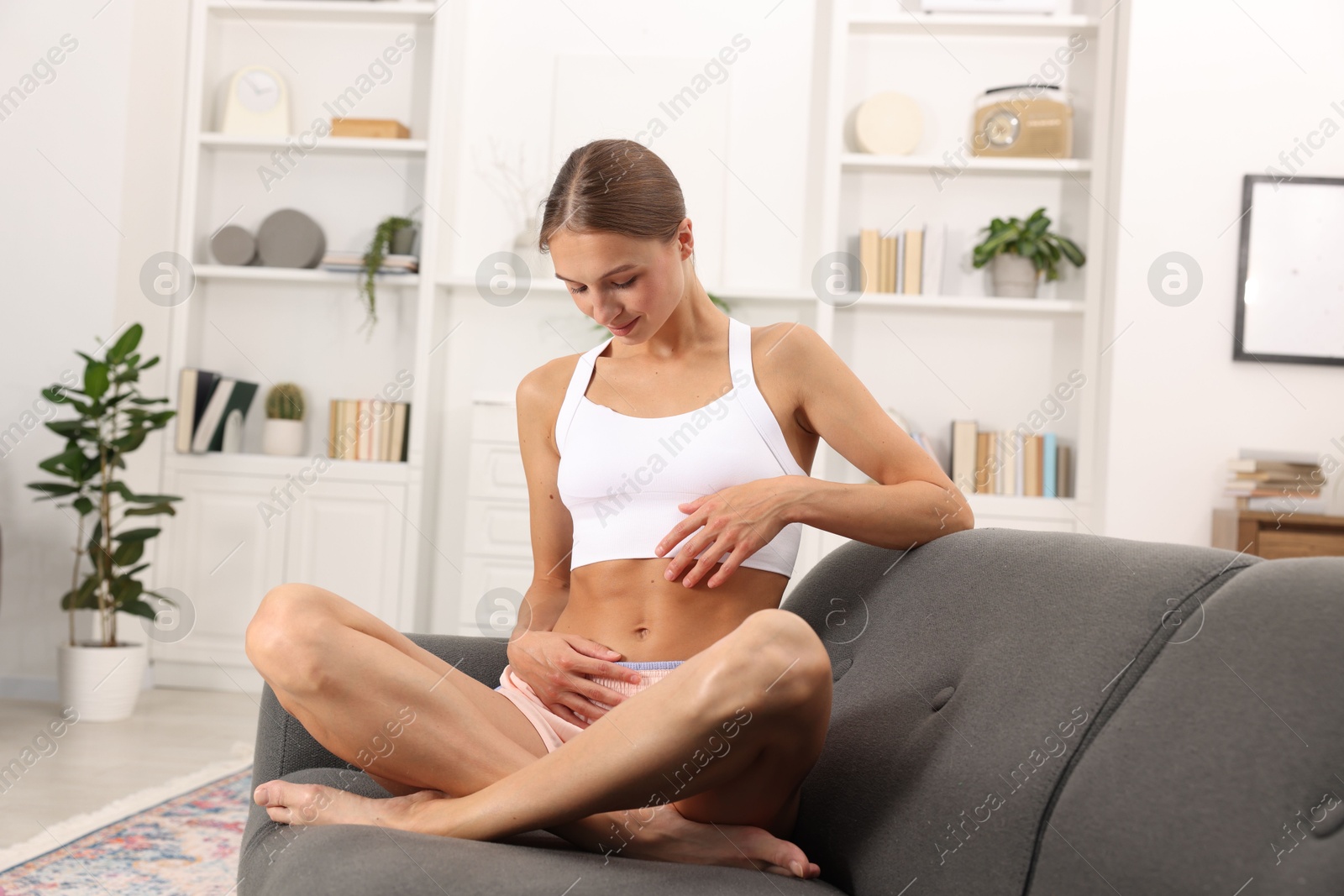 Woman with flat belly on sofa at home Photo of Woman with flat belly on sofa at home