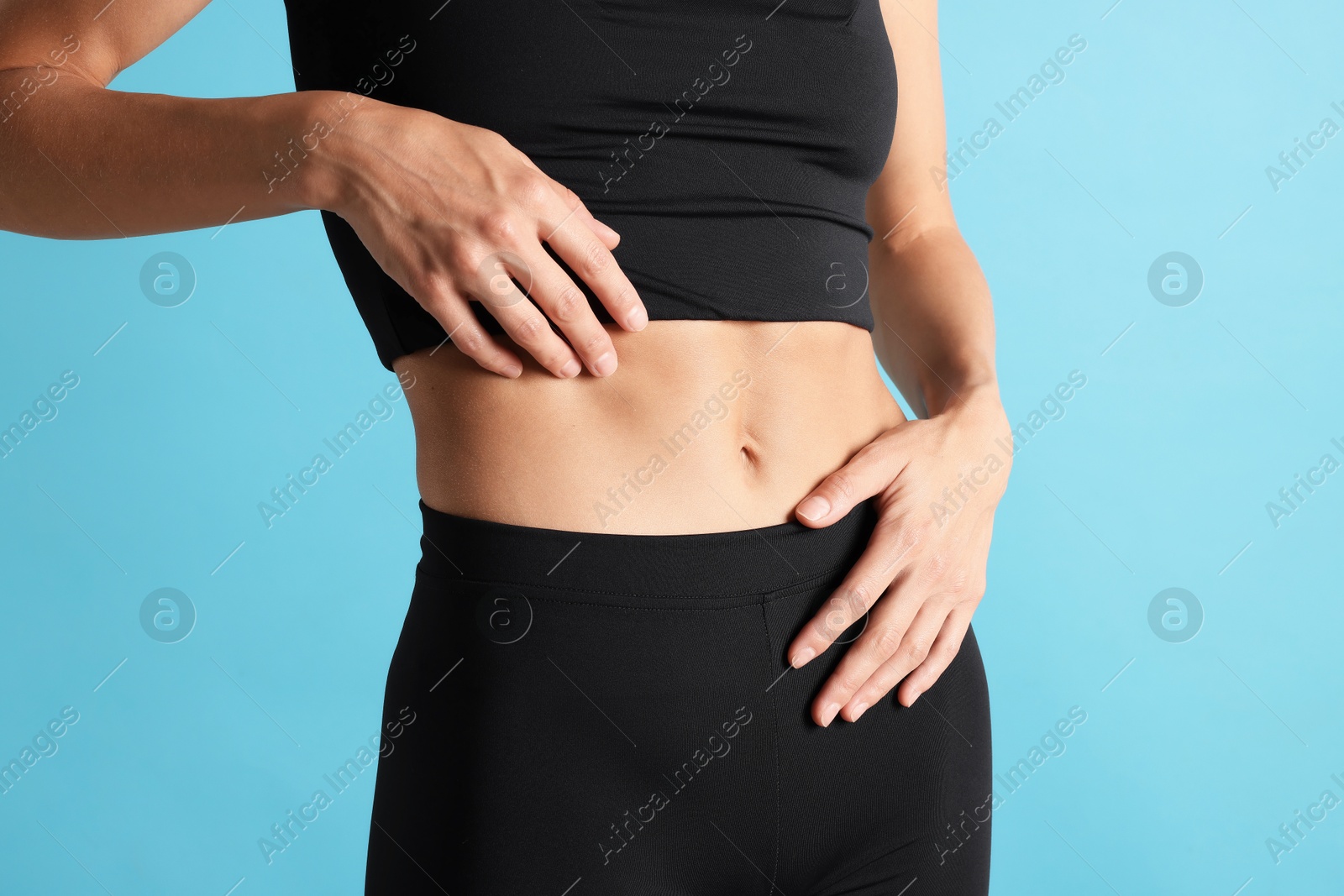 Photo of Woman with flat belly on light blue background, closeup