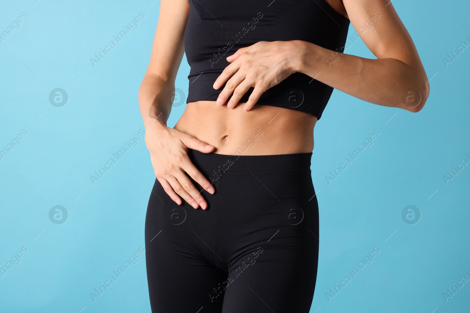 Woman with flat belly on light blue background, closeup Photo of Woman with flat belly on light blue background, closeup