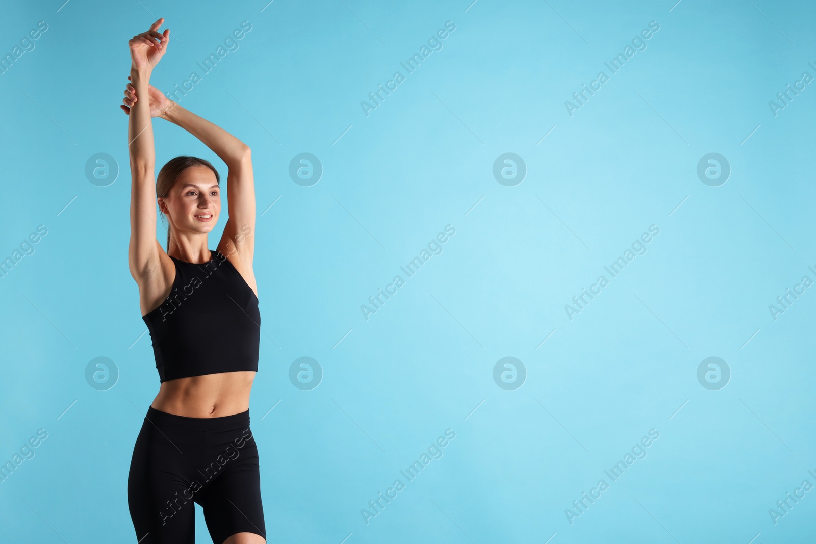 Woman with flat belly on light blue background, space for text Photo of Woman with flat belly on light blue background, space for text