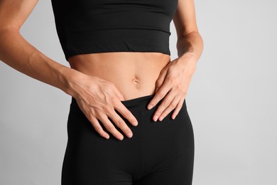 Photo of Woman with flat belly on light grey background, closeup
