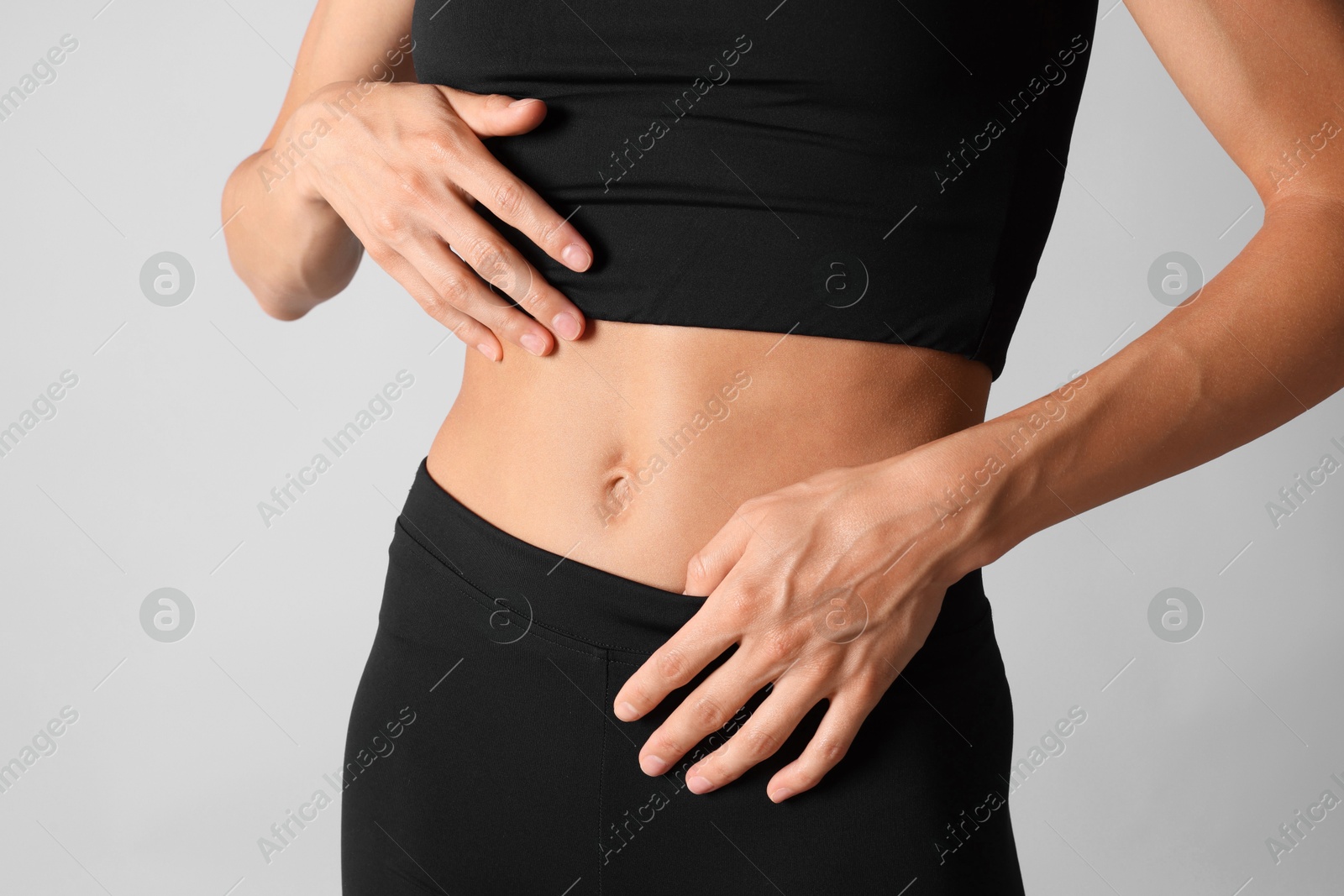 Woman with flat belly on light grey background, closeup Photo of Woman with flat belly on light grey background, closeup