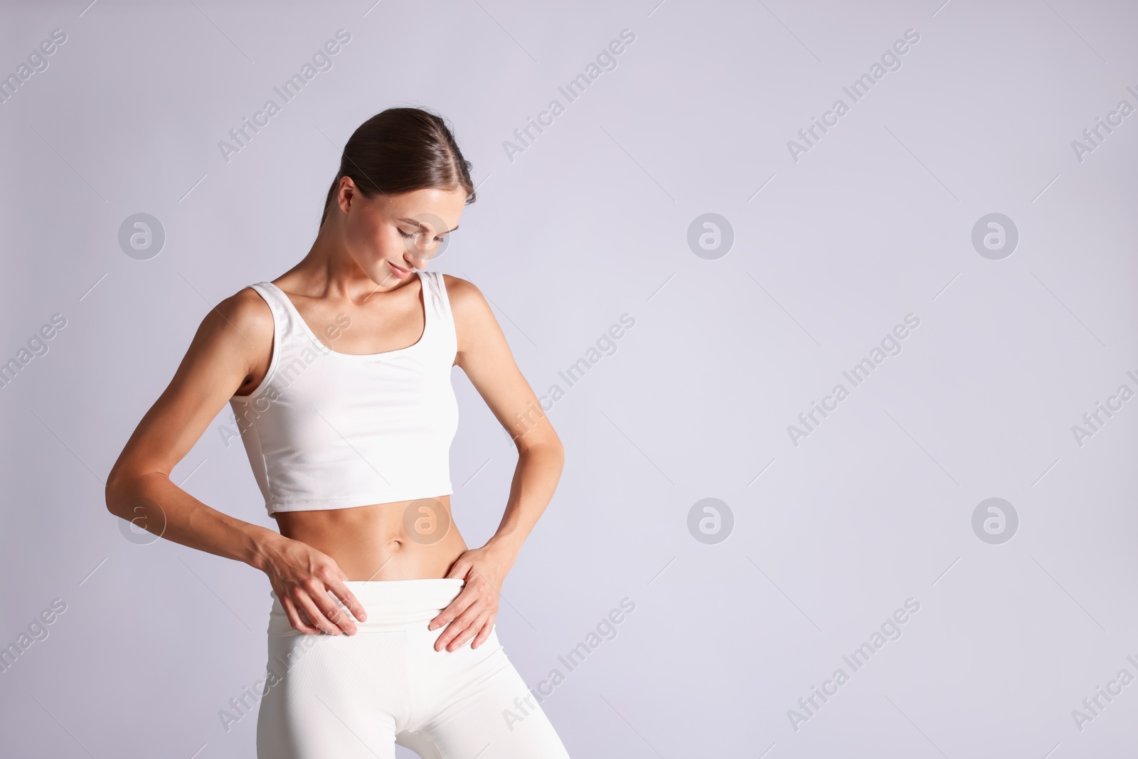 Woman with flat belly on light grey background, space for text Photo of Woman with flat belly on light grey background, space for text