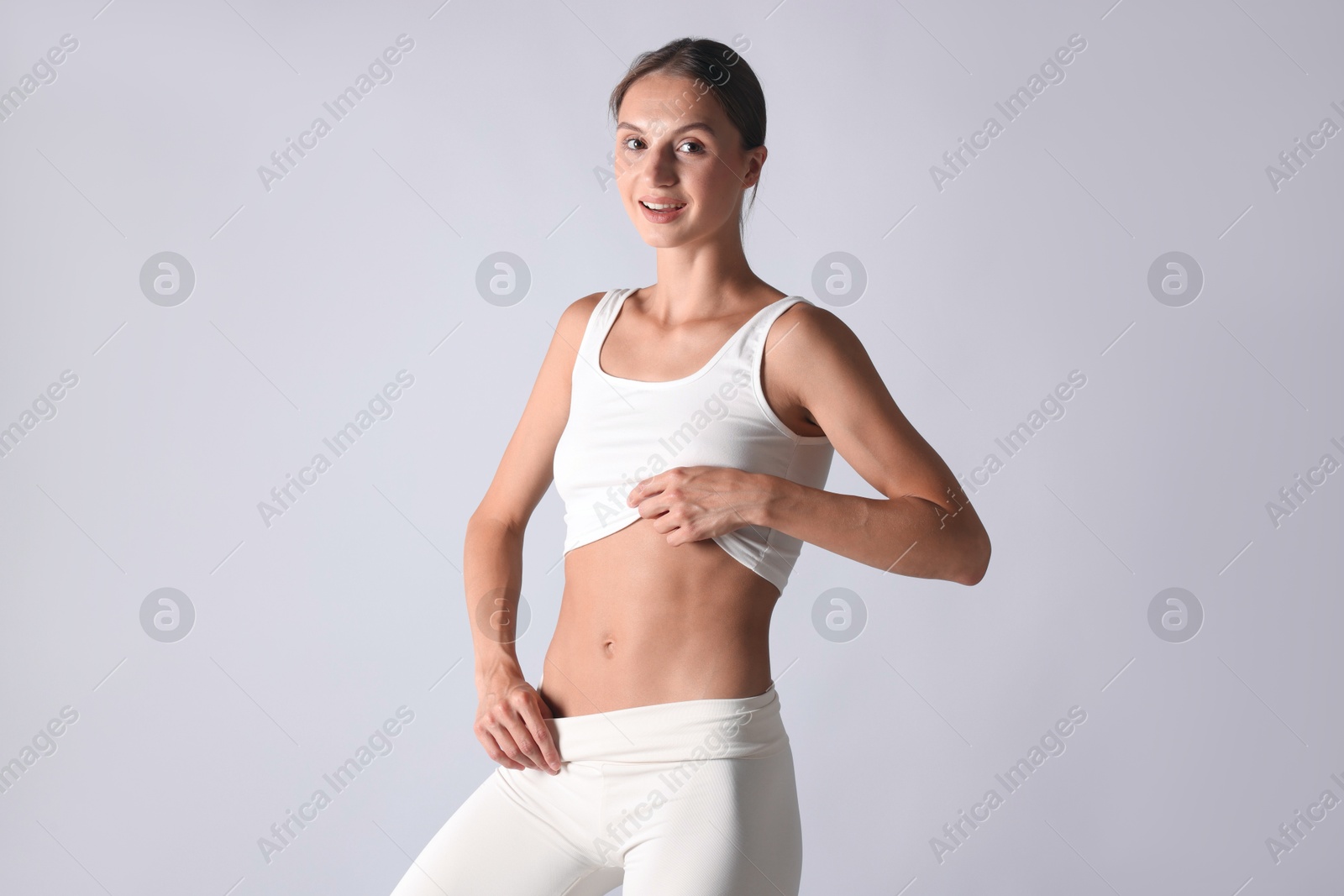 Woman with flat belly on light grey background Photo of Woman with flat belly on light grey background