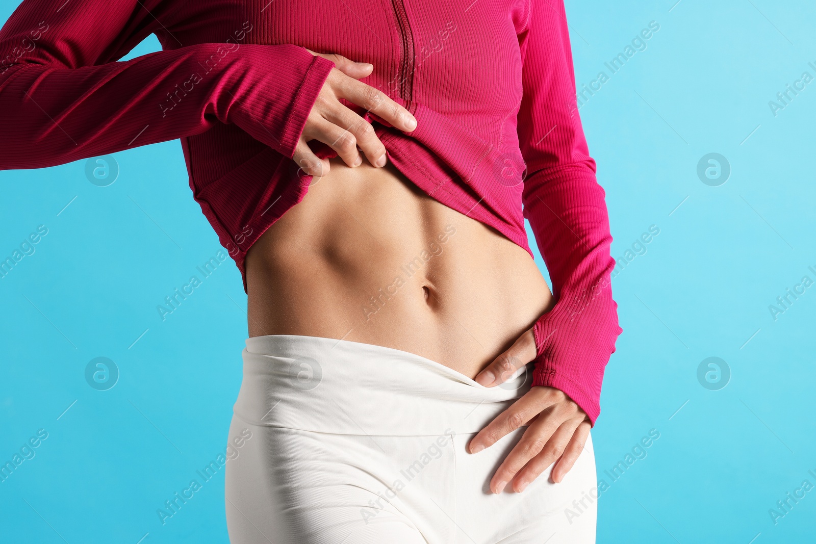 Woman with flat belly on light blue background, closeup Photo of Woman with flat belly on light blue background, closeup