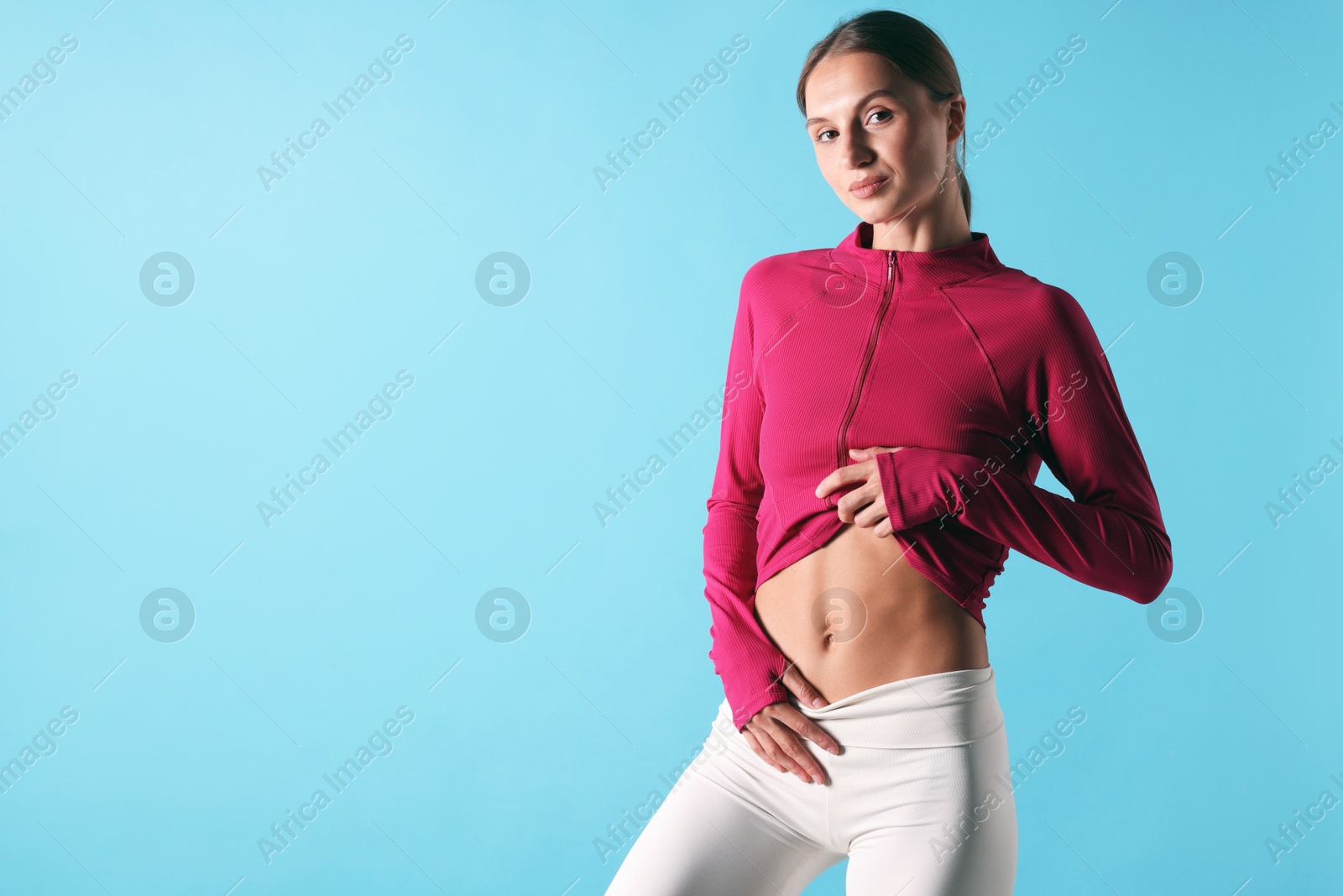 Woman with flat belly on light blue background, space for text Photo of Woman with flat belly on light blue background, space for text