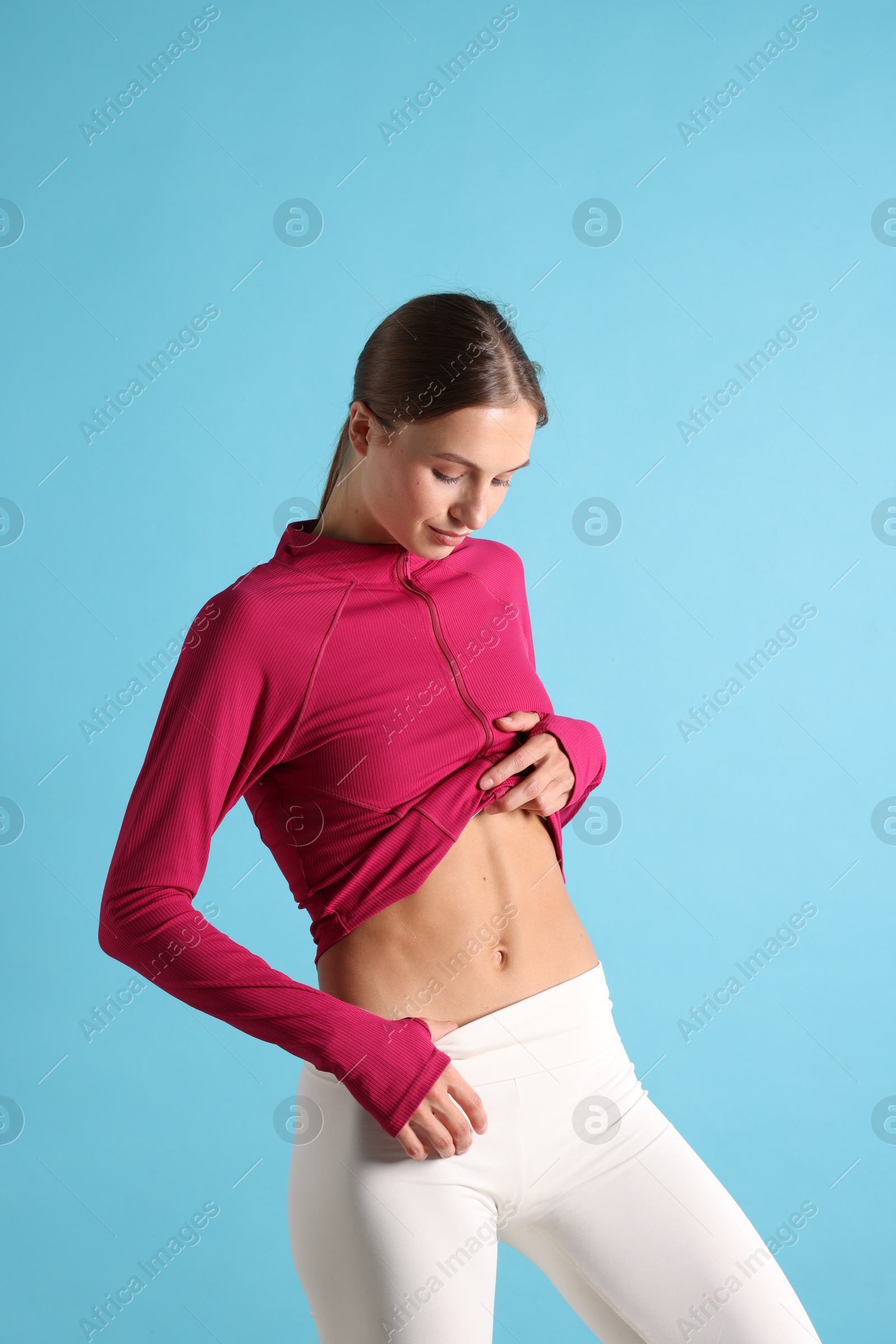 Woman with flat belly on light blue background Photo of Woman with flat belly on light blue background