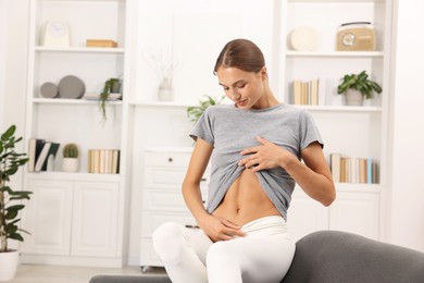 Photo of Woman with flat belly on sofa at home, space for text