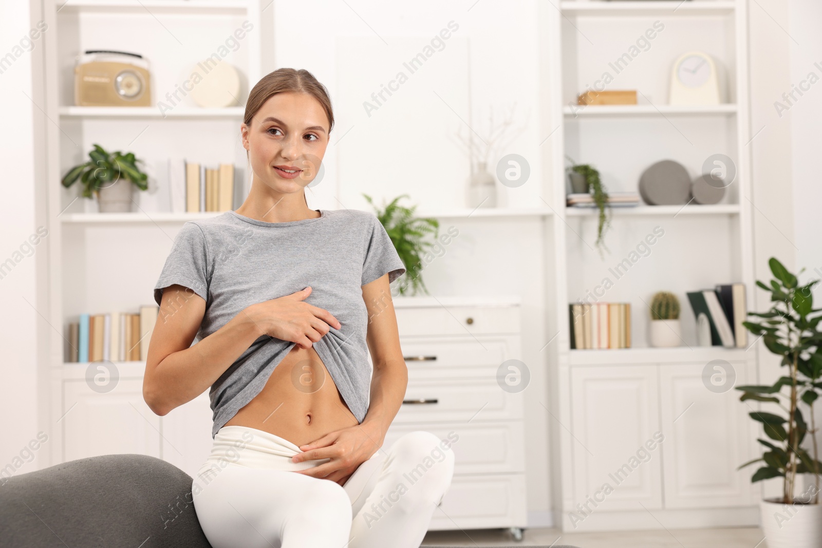 Woman with flat belly on sofa at home, space for text Photo of Woman with flat belly on sofa at home, space for text
