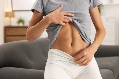 Photo of Woman with flat belly on sofa at home, closeup