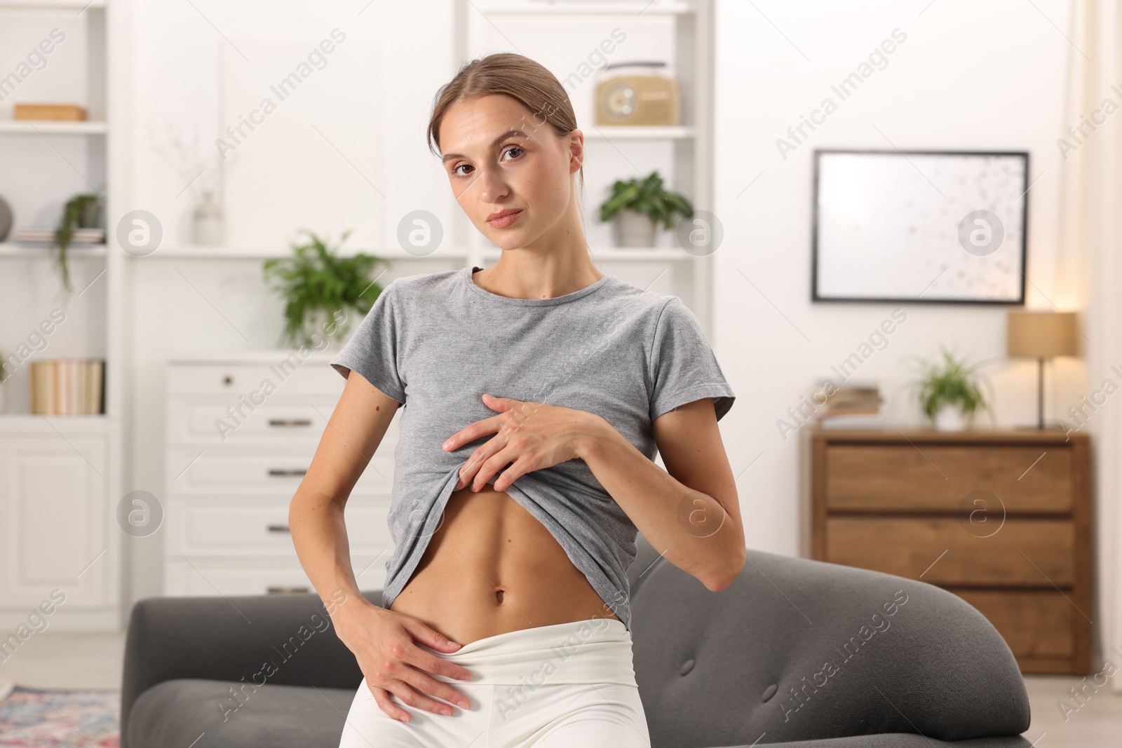 Woman with flat belly on sofa at home Photo of Woman with flat belly on sofa at home