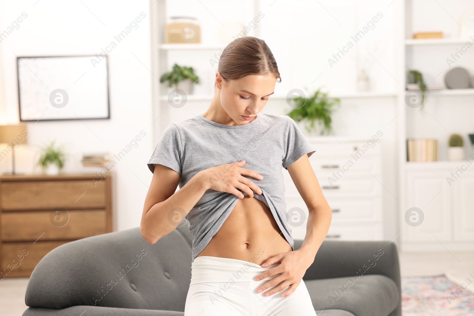 Woman with flat belly on sofa at home Photo of Woman with flat belly on sofa at home