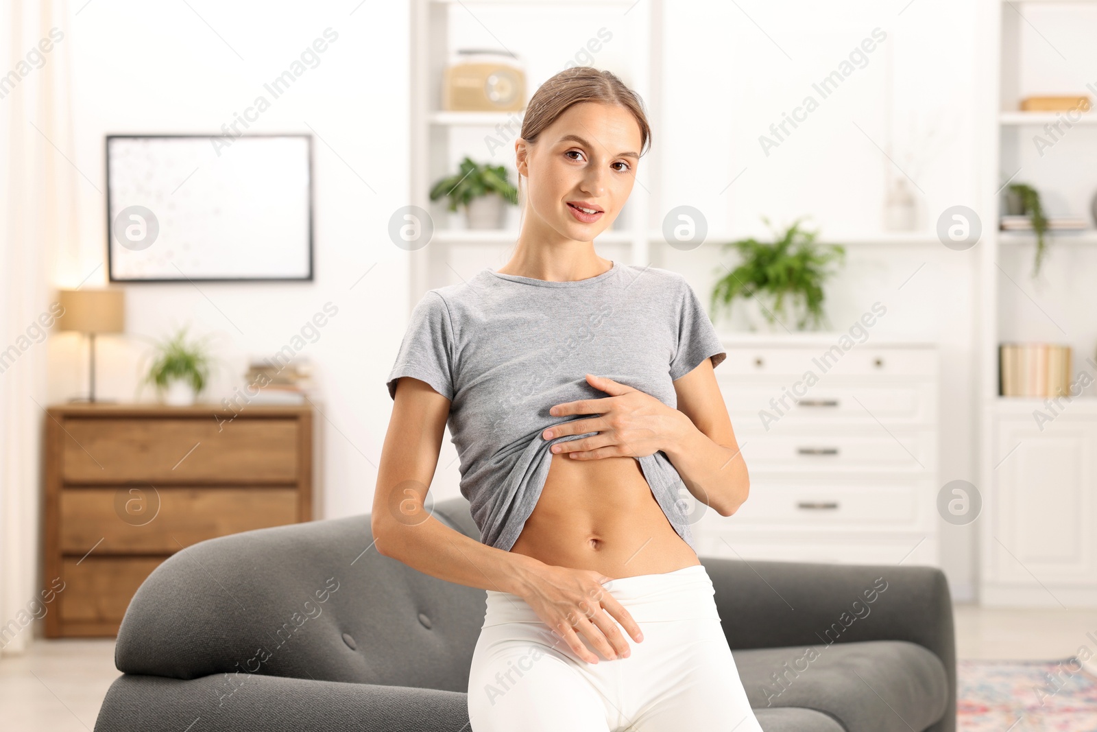 Woman with flat belly on sofa at home Photo of Woman with flat belly on sofa at home