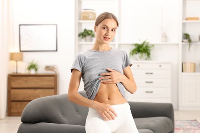 Photo of Woman with flat belly on sofa at home