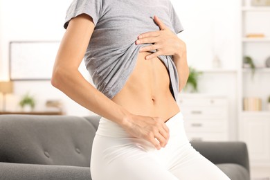 Photo of Woman with flat belly on sofa at home, closeup