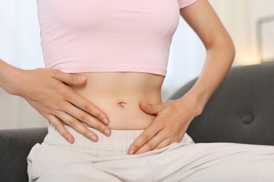 Photo of Woman with flat belly on sofa at home, closeup