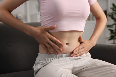 Photo of Woman with flat belly on sofa at home, closeup