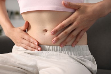 Photo of Woman with flat belly on sofa at home, closeup
