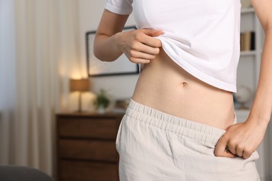 Photo of Woman with flat belly at home, closeup. Space for text