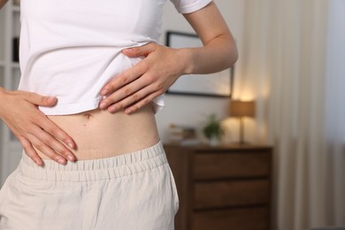 Photo of Woman with flat belly at home, closeup. Space for text