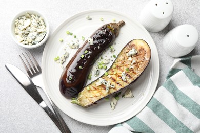 Photo of Slices of grilled eggplant with green onion and blue cheese on white table, flat lay