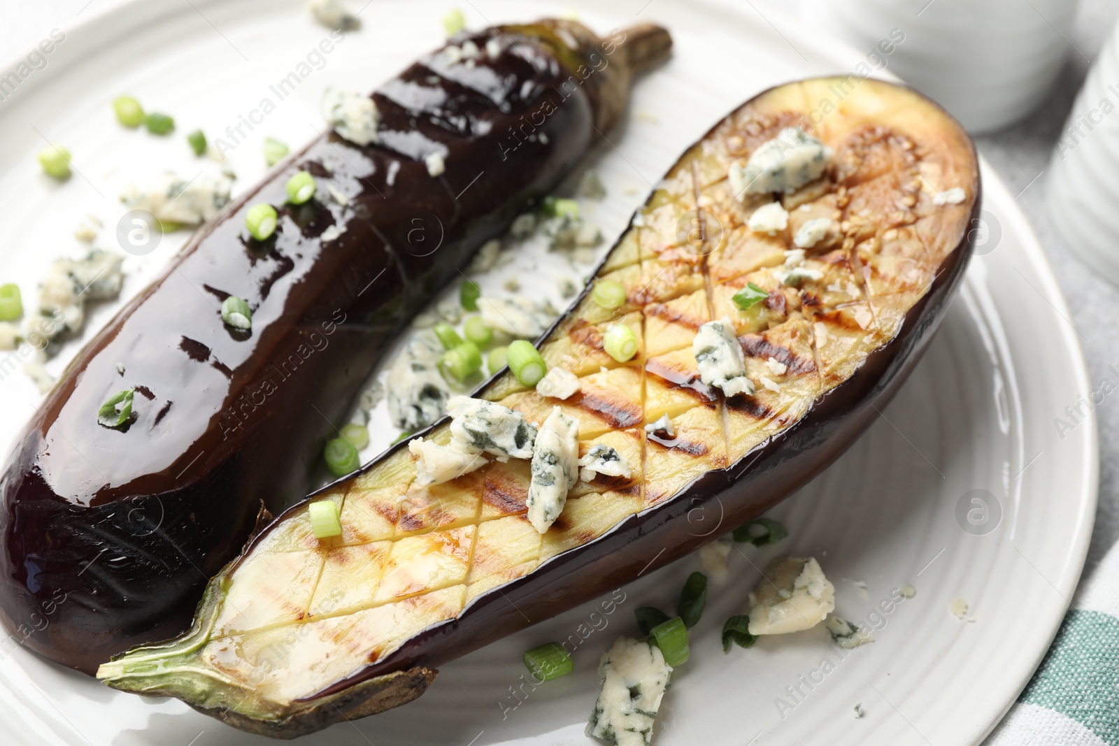 Slices of grilled eggplant with green onion and blue cheese on table Photo of Slices of grilled eggplant with green onion and blue cheese on table