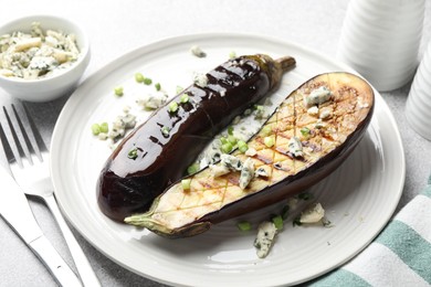Photo of Slices of grilled eggplant with green onion and blue cheese on white table