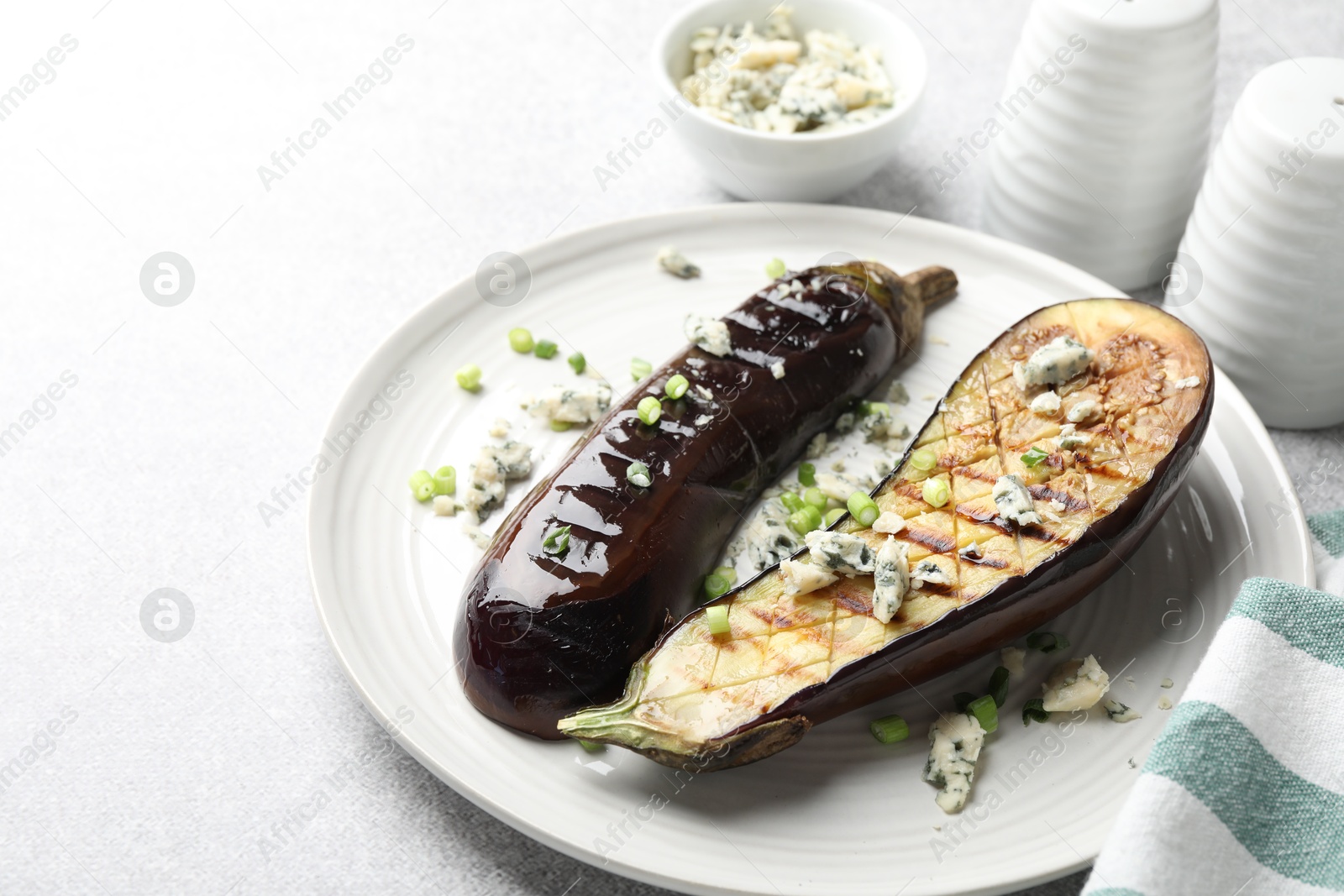 Slices of grilled eggplant with green onion and blue cheese on white table, closeup. Space for text Photo of Slices of grilled eggplant with green onion and blue cheese on white table, closeup. Space for text
