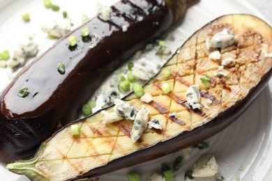 Photo of Slices of grilled eggplant with green onion and blue cheese on table, closeup