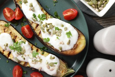 Photo of Slices of grilled eggplant with pumpkin seeds, tomatoes and yoghurt on wooden table, flat lay