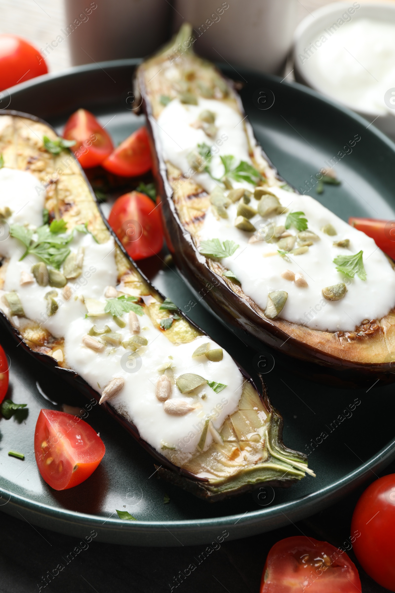 Photo of Slices of grilled eggplant with pumpkin seeds, tomatoes and yoghurt on table, closeup