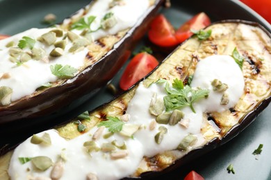 Photo of Slices of grilled eggplant with pumpkin seeds, tomatoes and yoghurt on table, closeup
